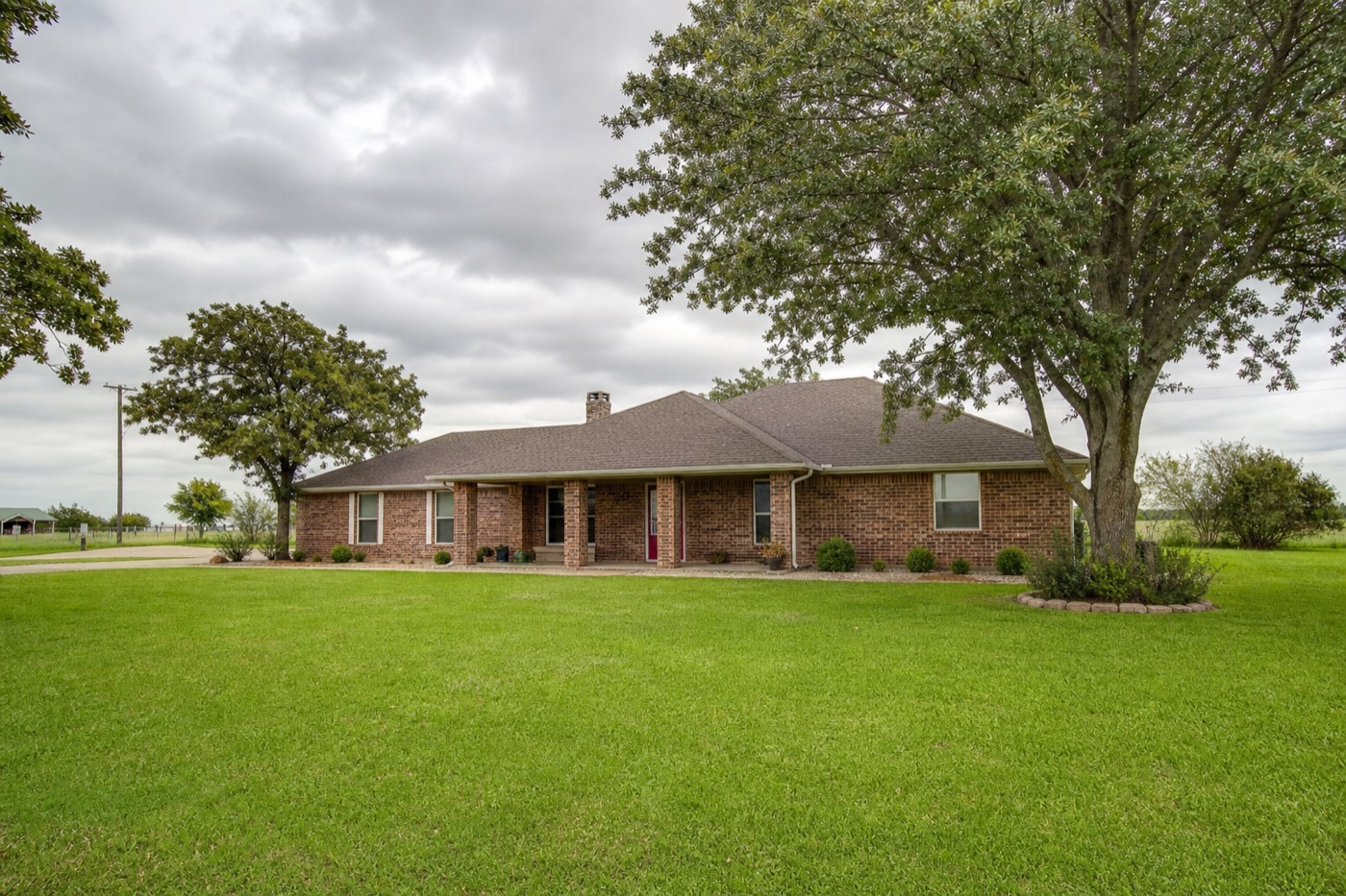 Single-story brick ranch home with mature trees and green lawn — typical Ellis County, Texas residential style
